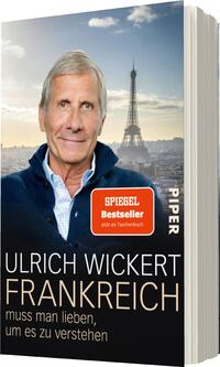 Das Buchcover zeigt einen älteren Mann mit grauen Haaren und freundlichem Ausdruck, der vor einer verschwommenen Stadtansicht von Paris steht, mit dem Eiffelturm im Hintergrund. Der obere Teil des Covers ist in sanften, hellen Farbtönen gehalten, während der Titel „FRANKREICH“ in großen, weißen Buchstaben über einem schwarzen Hintergrund präsent ist. Darunter steht der Untertitel „muss man lieben, um es zu verstehen“ in kleinerer Schrift. Am oberen Rand befindet sich ein rotes „SPIEGEL Bestseller“-Label.