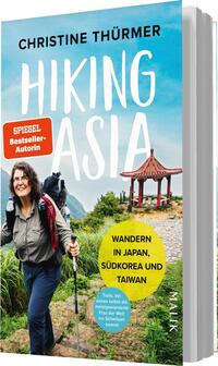 Das Buchcover zeigt eine lächelnde Frau mit einem Rucksack, die in einer hügeligen Landschaft steht, umgeben von üppigem Grün. Im Hintergrund ist ein traditionelles asiatisches Pavillon zu sehen, das von einer idyllischen Naturkulisse umgeben ist. Der Titel „HIKING ASIA“ ist in auffälliger, weißer Schrift platziert, während der Untertitel „WANDERN IN JAPAN, SÜDKOREA UND TAIWAN“ in gelber Schrift hervorgehoben ist. Oben links steht „SPIEGEL Bestseller-Autorin“ in roten Buchstaben.