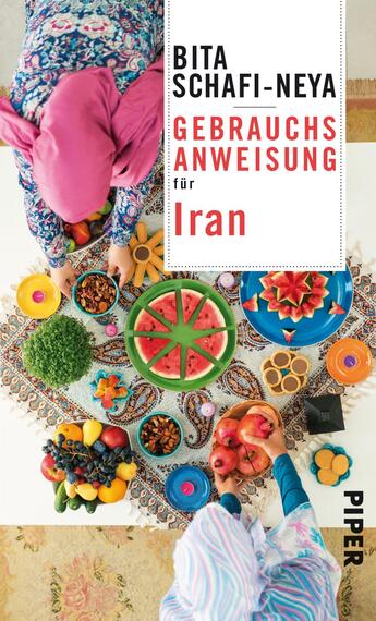 Das Buchcover zeigt eine von oben abgebildete Szene mit zwei Frauen, die in bunten, traditionell anmutenden Kleidern und Kopftüchern Lebensmittel auf einem reich dekorierten Tisch anrichten. Der Tisch ist mit verschiedenen Obstsorten, bunten Schalen und Gebäck gedeckt und bildet einen lebendigen Kontrast zu dem filigranen, gemusterten Tischtuch. Der Titel „Gebrauchsanweisung für Iran“ ist in großen, klaren Schriftarten platziert, wobei „Iran“ in kräftigem Rot hervorgehoben wird. Unten ist der Name der Autorin, Bita Schafi-Neya, abgedruckt.
