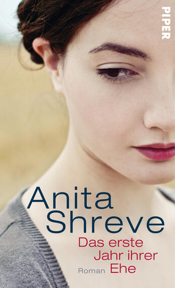 Das Buchcover zeigt das Porträt einer jungen Frau mit einem nachdenklichen Ausdruck. Ihr Gesicht ist sanft beleuchtet, während der Hintergrund eine unscharfe, goldene Feldlandschaft zeigt, die eine ruhige Atmosphäre vermittelt. Der Titel „Das erste Jahr ihrer Ehe“ ist in blauer Schrift prominent platziert, die Schriftart ist modern und klar. Der Autorennamen „Anita Shreve“ steht in großen, auffälligen Buchstaben oben, ebenfalls in Blau, während das Verlagslogo „PIPER“ in der oberen Ecke rechts abgebildet ist.