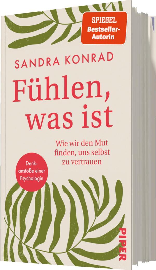 Das Buchcover zeigt eine helle, beige Hintergrundfarbe mit großflächigen grünen Pflanzenmotiven, die lebendige Blätter darstellen. Der Titel „Fühlen, was ist“ ist in kräftigem Rot in einer modernen Schriftart gestaltet und steht prominent im oberen Drittel. Darunter befindet sich der Untertitel „Wie wir den Mut finden, uns selbst zu vertrauen“ in einer kleineren, grauen Schriftart. Oben links ist ein rotes Symbol mit dem Text „SPIEGEL Bestseller-Autorin“ platziert, während unten links ein roter Kreis mit dem Text „Denkanstöße einer Psychologin“ zu sehen ist. Der Verlagsname „Piper“ erscheint in kleiner Schrift am Fuß des Covers.