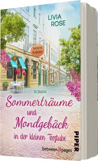 Das Buchcover zeigt eine malerische Straße mit bunten Gebäuden und üppigem Grün, das von blühenden Pflanzen umrahmt wird. In der Mitte steht ein Schild mit der Aufschrift „MOON BAKERY“. Die Titelzeile „Sommerträume und Mondgebäck“ ist in einem verspielten rosa Schriftzug platziert, während der Name „Livia Rose“ in einem kontrastierenden Blau darüber steht. Der Untertitel „Roman“ ergänzt die Gestaltung, die eine einladende und verträumte Atmosphäre vermittelt. Die gesamte Farbpalette ist hell und freundlich, mit einem Sommerflair.