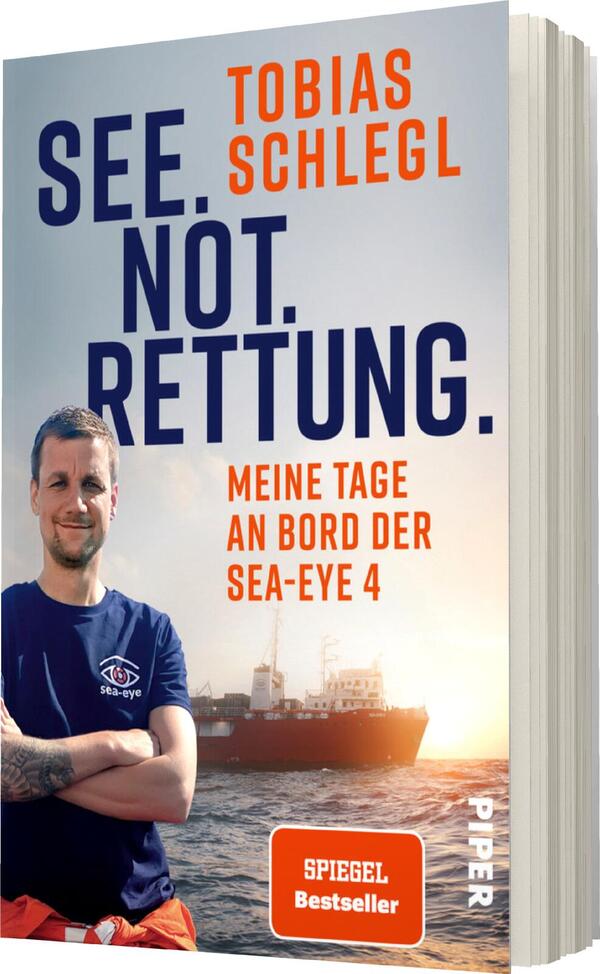 Das Buchcover zeigt einen Mann in blauer Kleidung mit einem Logo auf der Brust, der in die Kamera lächelt. Im Hintergrund ist ein Schiff auf dem Wasser zu sehen. Der obere Teil des Covers trägt den Titel „SEE. NOT. RETTUNG.“ in großen, fetten, blauen Buchstaben. Darunter steht der Untertitel „MEINE TAGE AN BORD DER SEA-EYE 4.“ in Grau. Das Cover vermittelt eine ernste, aber auch hoffnungsvolle Atmosphäre. Auf dem Cover befindet sich ein rotes Label mit der Aufschrift „SPIEGEL Bestseller“.