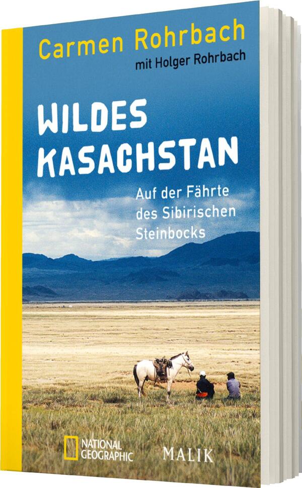 Das Buchcover zeigt eine weite, offene Landschaft in Kasachstan unter einem klaren, blauen Himmel. Im Vordergrund sitzen zwei Personen auf dem Boden neben einem Pferd. Der Titel „WILDES KASACHSTAN“ ist groß und in auffälliger, weißer Schrift platziert. Darunter steht in kleinerer Schrift die Unterzeile „Auf der Fähre des Sibirischen Steinbocks“. Die Farben sind sanft und natürlich, mit einem gelben Buchrücken, der dem Cover eine freundliche Note verleiht. Die Autoren Carmen Rohrbach und Holger Rohrbach sind oben benannt.