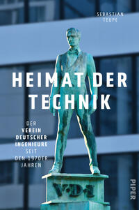 Das Buchcover zeigt eine patinagrüne Bronzestatue eines stehenden Mannes auf einem Sockel mit der Inschrift VDI vor einer unscharfen blau-grauen Glasfassade. Über der Figur prangt der Titel in großen weißen serifenlosen Großbuchstaben „HEIMAT DER TECHNIK“. Links steht die Unterzeile „Der Verein Deutscher Ingenieure seit den 1970er Jahren“. Oben rechts ist der Autorenname Sebastian Teupe. Die Stimmung wirkt nüchtern und institutional.