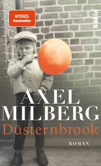Das Buchcover zeigt ein retro-inspiriertes Schwarz-Weiß-Foto eines Kindes, das einen grau-weißen Mantel und eine Mütze trägt. Das Kind blickt direkt in die Kamera und hält einen großen, leuchtend orangefarbenen Ball in der Hand. Im oberen Bereich befindet sich ein rotes Label mit der Aufschrift „SPIEGEL Bestseller“. Der Titel „Düsternbrook“ steht in großen, weißen Buchstaben, darunter der Name des Autors „AXEL MILBERG“ in etwas kleinerer Schriftgröße. Das Cover vermittelt eine nostalgische und melancholische Stimmung.