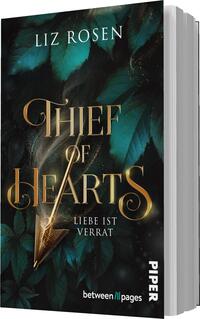 Das Buchcover zeigt einen dunklen, mystischen Hintergrund mit grünen Blättern und goldenen Akzenten. In der Mitte des Covers steht der Titel „THIEF OF HEARTS“ in eleganter, geschwungener Schrift, umgeben von einem Pfeil, der von Glitzern umgeben ist. Unter dem Titel befindet sich der Schriftzug „LIEBE IST VERRAT“ in schlichterer Schrift. Der Name der Autorin, Liz Rosen, ist am oberen Rand in weißer Schrift platziert. In der unteren Ecke ist das Verlagslogo „PIPER“ zu sehen.