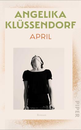 Das Buchcover zeigt ein helles, minimalistisches Design. Im oberen Bereich steht der Name der Autorin „Angelika Klüssendorf“ in großen, grünen Buchstaben. Darunter befindet sich der Titel „APRIL“ in auffälligem, orangefarbenem Schriftzug. Zentral ist ein Schwarz-Weiß-Foto einer Person, die mit nach hinten geneigtem Kopf dasteht, und einen nachdenklichen Ausdruck zeigt. Am unteren Rand ist das Wort „Roman“ in kleinerer Schrift zu sehen, sowie das Verlagslogo in dezenterer Position.