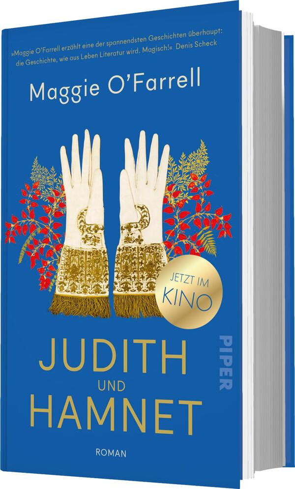 Das Buchcover zeigt einen tiefblauen Hintergrund mit zwei weißen, handschuhtragenden Händen, die golden verzierte Textilien halten. Um die Hände sind vereinzelte rote Blüten abgebildet, die dem Cover eine lebendige Note verleihen. Der Titel „JUDITH UND HAMNET“ steht in großen goldenen Buchstaben, während der Autorenname Maggie O’Farrell in weißer Schrift darüber platziert ist. Ein runder Button mit dem Text „JETZT IM KINO“ ist ebenfalls prominent dargestellt. Die Gesamtatmosphäre vermittelt eine Mischung aus Eleganz und Emotionalität.