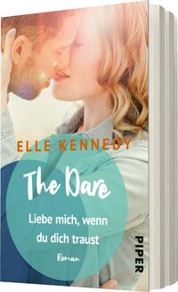 Das Buchcover zeigt ein romantisches Paar, das sich kurz vor einem Kuss befindet. Die Farben sind warm und sanft, mit einem hellen Hintergrund, der eine freundliche Atmosphäre schafft. Der Titel „The Dare“ ist in einer verspielten Schriftart in Weiß gehalten und hebt sich vor einem türkisfarbenen Kreis ab. Untertitel und Autorennamen sind in orange und Weiß dargestellt. Das Wort „Roman“ ist in kleiner Schrift am unteren Rand platziert.