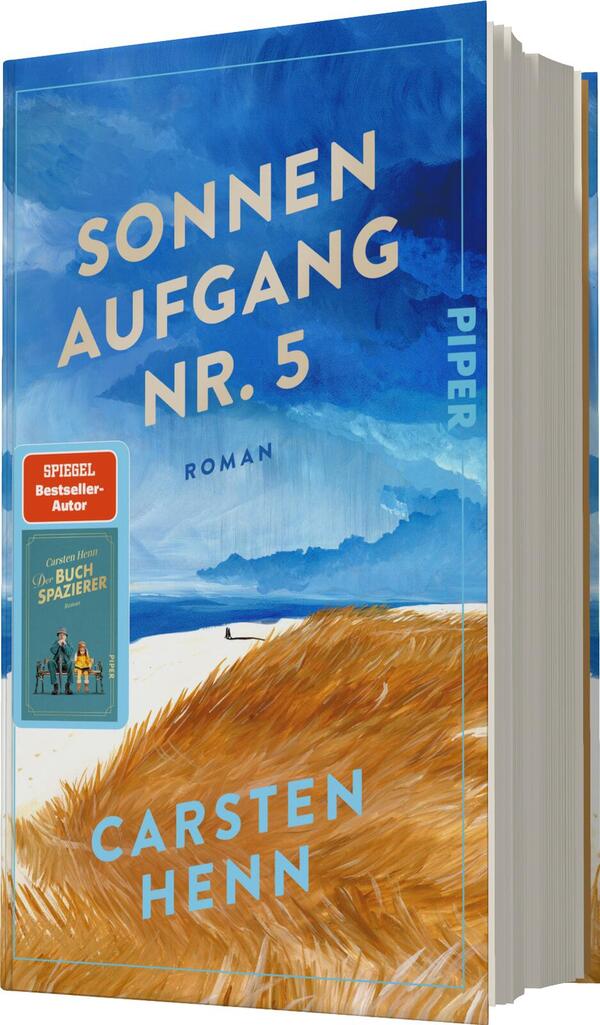 Das Buchcover zeigt einen weiten, hellblauen Himmel mit sanften, weißen Wolken und einem Horizont, der auf das Meer blickt. Im Vordergrund erstrecken sich goldene, weiche Grasstrukturen. Oben steht in großem, klaren Weiß „SONNEN AUFGANG NR. 5“, darunter in kleinerer Schrift „ROMAN“. Am linken oberen Rand ist ein rotes Badge mit der Aufschrift „SPIEGEL Bestseller-Autor“ zu sehen. Der Name des Autors, „Carsten Henn“, erscheint in dezentem Blau am unteren Rand.