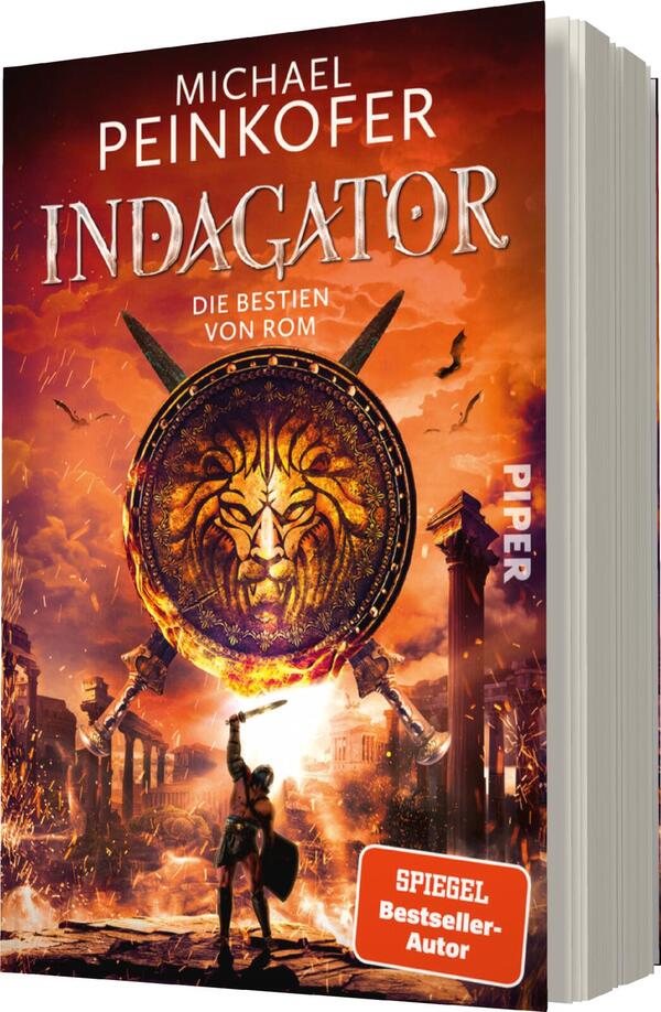 Das Buchcover zeigt eine dynamische, dramatische Szenerie mit einem farbenfrohen Himmel in Orange- und Rottönen. Im Zentrum befindet sich ein großer, runder Schild mit dem Gesicht eines Löwen, umgeben von klassischer römischer Architektur. Im Vordergrund steht eine männliche Figur in Rüstung, die einen Schild hält. Der Titel „INDAGATOR“ ist in großen, auffälligen Buchstaben über dem Schild platziert, während der Untertitel „DIE BESTIEN VON ROM“ darunter in kleinerer Schrift erscheint. Oben steht der Autor „Michael Peinkofer“.
