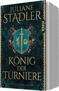 Das Buchcover zeigt eine elegante, smaragdgrüne Hintergrundfarbe mit filigranen, goldenen Verzierungen. Im Mittelpunkt befindet sich ein Wappen mit einem Schwert und floralen Motiven, flankiert von stilisierten Löwen. Der Titel „König der Turniere“ ist in großen, goldenen Buchstaben platziert, während der Autorennamen „Juliane Stadler“ in einer etwas kleineren Schrift oben erscheint. Der Zusatz „Historischer Roman“ ist ebenfalls in goldener Schrift angegeben. Die gesamte Gestaltung vermittelt eine atmosphärische, mittelalterliche Stimmung.