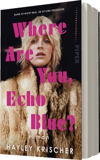 Das Buchcover zeigt ein Portrait einer blonden Frau mit auffälligen Sommersprossen, die in einem luxuriösen, hellbraunen Pelzmantel gekleidet ist. Der Hintergrund ist dunkel und verleiht dem Cover eine dramatische Atmosphäre. In großen, fetten, pinken Buchstaben steht der Titel „Where Are You, Echo Blue?“ über ihrem Kopf, während der Autorenname „HAYLEY KRISCHER“ in kleinerer Schrift darunter platziert ist. Das Wort „roman“ befindet sich ebenfalls in der unteren Hälfte des Covers.