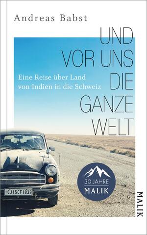 Das Buchcover zeigt ein klassisches Auto auf einer weitläufigen, trockenen Straße unter einem klaren blauen Himmel. Der Titel „UND VOR UNS DIE GANZE WELT“ ist in großen, modernen Buchstaben platziert, während der Untertitel „Eine Reise über Land von Indien in die Schweiz“ in kleinerer Schrift darunter steht. Oben links befindet sich der Autorennamen Andreas Babst. In der unteren Ecke ist ein runder Button mit dem Text „30 Jahre MALIK“ abgebildet.
