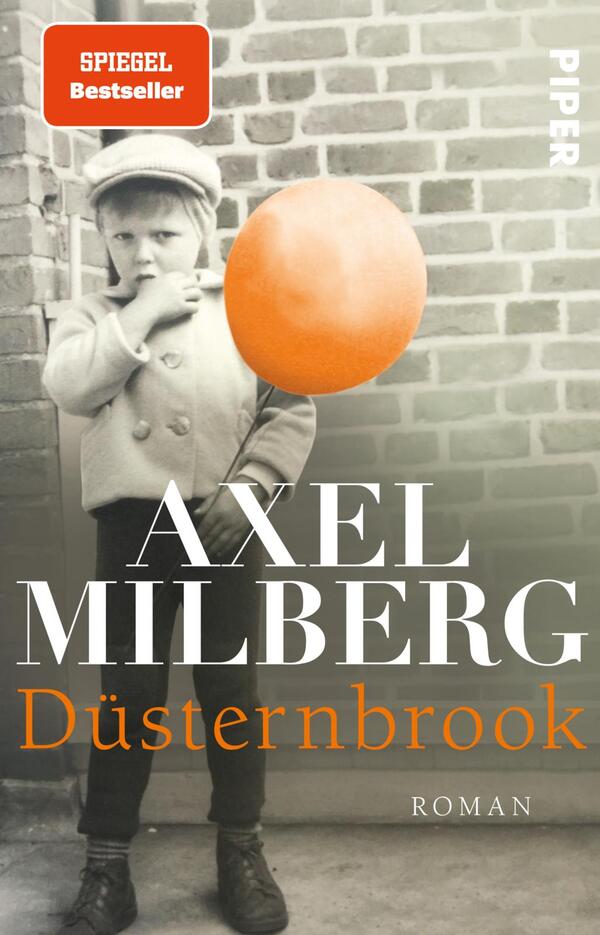 Das Buchcover zeigt ein schwarz-weißes Portrait eines kleinen Jungen, der in einer urbanen Umgebung mit Ziegelmauer steht. Er trägt eine schlichte Jacke und eine Mütze. In seiner rechten Hand hält er einen großen orangefarbenen Luftballon, der einen warmen Kontrast zur monochromen Umgebung bietet. Der Titel „Düsternbrook“ ist in großen, weißen Buchstaben auf der unteren Hälfte des Covers zu lesen, während der Autor „AXEL MILBERG“ in schwarz darüber steht. Oben links ist das Siegel „SPIEGEL Bestseller“ platziert.