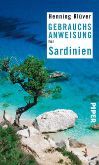 Das Buchcover zeigt einen malerischen Küstenabschnitt Sardiniens mit kristallklarem, türkisblauem Wasser und einem hellen Sandstrand. Ein einsamer Baum steht im Vordergrund und kontrastiert mit der grünen Umgebung. Der Titel „GEBRAUCHSANWEISUNG für Sardinien“ ist in großen, weißen Buchstaben auf einem blauen Hintergrund platziert. Der Autor Henning Klüver wird in einem schmalen, weißen Feld oben genannt. Das Verlagslogo „PIPER“ befindet sich am rechten unteren Rand in vertikaler Schrift.