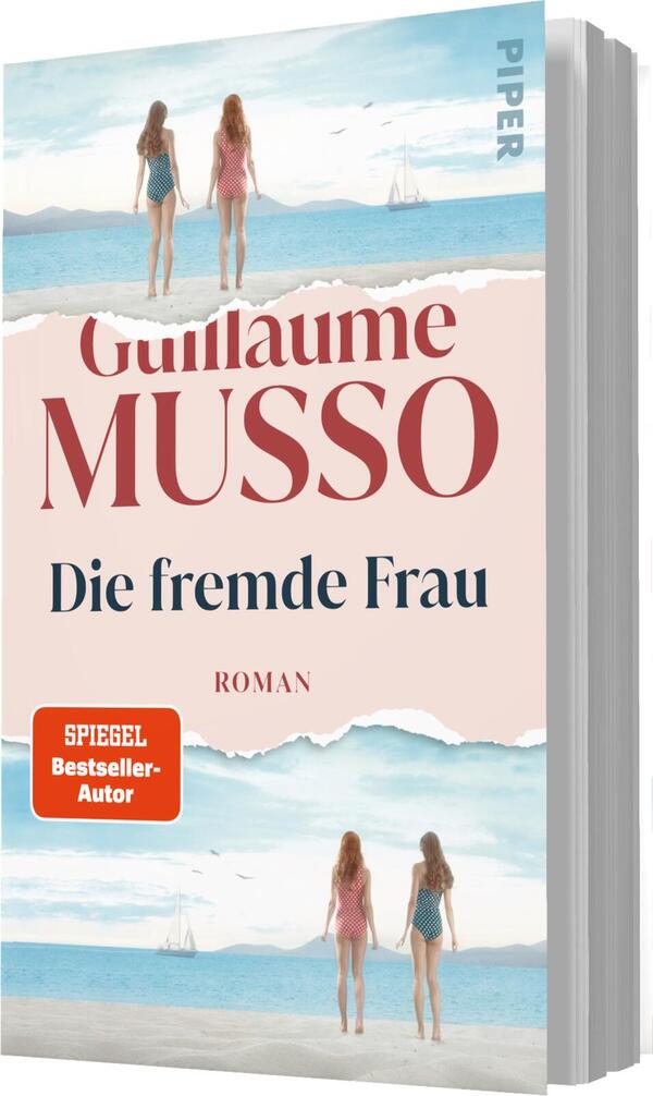 Das Buchcover zeigt zwei Frauen in Bademode, die am Strand stehen und auf das Wasser blicken. Der Hintergrund ist in sanften Blau- und Sandtönen gehalten, vermittelt eine sommerliche, entspannte Atmosphäre. Der Titel „Die fremde Frau“ ist in eleganter, blauer Schrift deutlich sichtbar, während der Autor „Guillaume Musso“ in einer kräftigen, rotbraunen Schrift darüber steht. Unten links befindet sich ein orangefarbener Button mit dem Text „SPIEGEL Bestseller-Autor“.