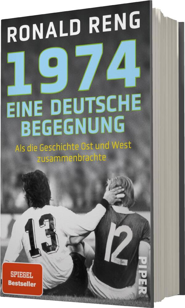 Das Buchcover zeigt eine schwarz-weiße Fotografie von zwei Fußballspielern, die sich auf einem Spielfeld gegenüberstehen. Der Spieler mit der Nummer 13 sitzt links, während der Spieler mit der Nummer 12 rechts sitzt und seine Hand auf die Schulter des anderen legt. Oben steht der Titel „1974“ in hellblauer Schrift, gefolgt von „EINE DEUTSCHE BEGEGNUNG“ in weißer Farbe. Darunter ist der Untertitel „Als die Geschichte Ost und West zusammenbrachte“ in kleinerer, schwarzer Schrift. Das Cover trägt das Label „SPIEGEL Bestseller“ in rotem Kästchen und das Verlagslogo „PIPER“ unten rechts.