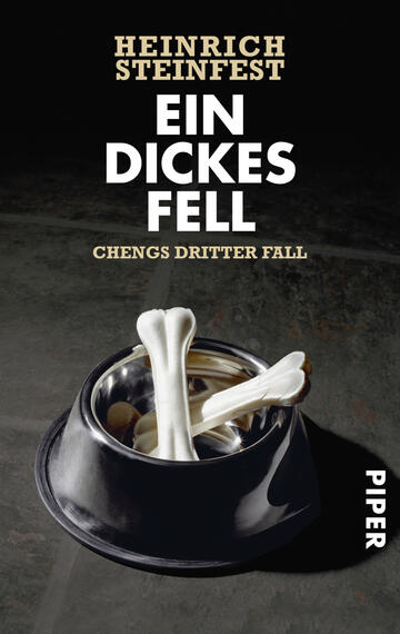 Das Buchcover zeigt einen schwarzen Hundenapf, der gefüllt ist mit zwei weißen Knochen, auf einem dunklen, texturierten Untergrund. Der Titel „Ein dickes Fell“ steht prominent in großen, fettgedruckten, goldenen Buchstaben oben, gefolgt von dem Zusatz „Chengs dritter Fall“ in etwas kleinerer, heller Schrift. Der Autor „Heinrich Steinfest“ ist ebenfalls in goldener Schrift am oberen Rand abgebildet. Am unteren rechten Rand findet sich der Verlagsname „PIPER“ in schlichter Schrift. Die Gesamtatmosphäre ist modern und ansprechend.