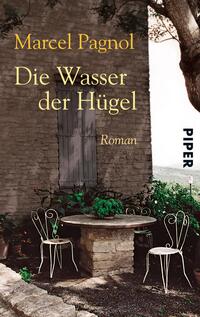 Das Buchcover zeigt eine idyllische Szene mit einem rustikalen Steinbau im Hintergrund und einem runden Tisch aus Stein im Vordergrund. Zwei schlichte weiße Eisenstuhl stehen auf der linken Seite. Der Titel „Die Wasser der Hügel“ ist in eleganter, goldener Schrift mittig platziert, darüber der Autorname Marcel Pagnol. Am rechten Rand befindet sich das Verlagslogo „PIPER“ in einfacher typografischer Schrift. Die sanften Farben und der ländliche Charakter vermitteln eine ruhige, einladende Atmosphäre.