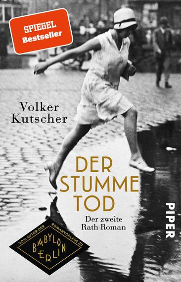 Das Buchcover zeigt eine schwarz-weiß Fotografie einer Frau in einem weißen Kleid, die mit Schwung über eine regennasse Straße läuft. Im Hintergrund sind historische Gebäude und weitere Personen sichtbar, was eine nostalgische Atmosphäre erzeugt. Der Titel „DER STUMME TOD“ ist in großen, goldenen Buchstaben prominent platziert, unterlegt mit dem Text „Der zweite Rath-Roman“. Der Autor „Volker Kutscher“ steht über dem Titel in schlichter, schwarzer Schrift. Ein rotes Label mit der Aufschrift „SPIEGEL Bestseller“ ziert die obere linke Ecke. Das Verlagslogo „PIPER“ ist in der unteren rechten Ecke abgebildet.