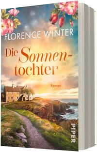 Das Buchcover zeigt am oberen Rand pinke und rote Wildrosen vor einem abendlichen Himmel in Pastellblau, Orange und Gelb. Zentral links oben steht der Autorname „Florence Winter“, darunter groß der Titel „Die Sonnentochter“ in orange-roter Serifenschrift; klein rechts darunter der Zusatz „Roman“. Unten links ein Küstenhaus auf einem grasbewachsenen Pfad über Klippen zum Meer, Stimmung ruhig und warm.