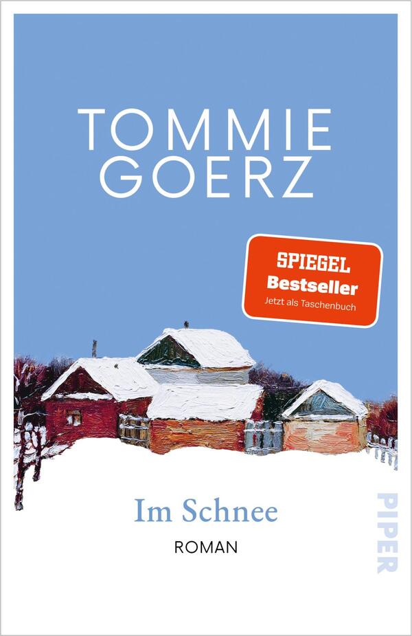 Das Buchcover zeigt einen hellblauen Himmel als Hintergrund, oben in großer weißer, serifenloser Versalien-Typografie der Autorenname TOMMIE GOERZ. Darunter eine leicht impressionistische Winterlandschaft mit roten Backsteinhäusern und schneebedeckten Dächern. Rechts ein oranger Button mit dem Text „SPIEGEL Bestseller Jetzt als Taschenbuch“. Titel „Im Schnee“ steht in gedecktem Blau in serifenbetonter Schrift, darunter klein „ROMAN“. Ruhige, winterliche Stimmung.
