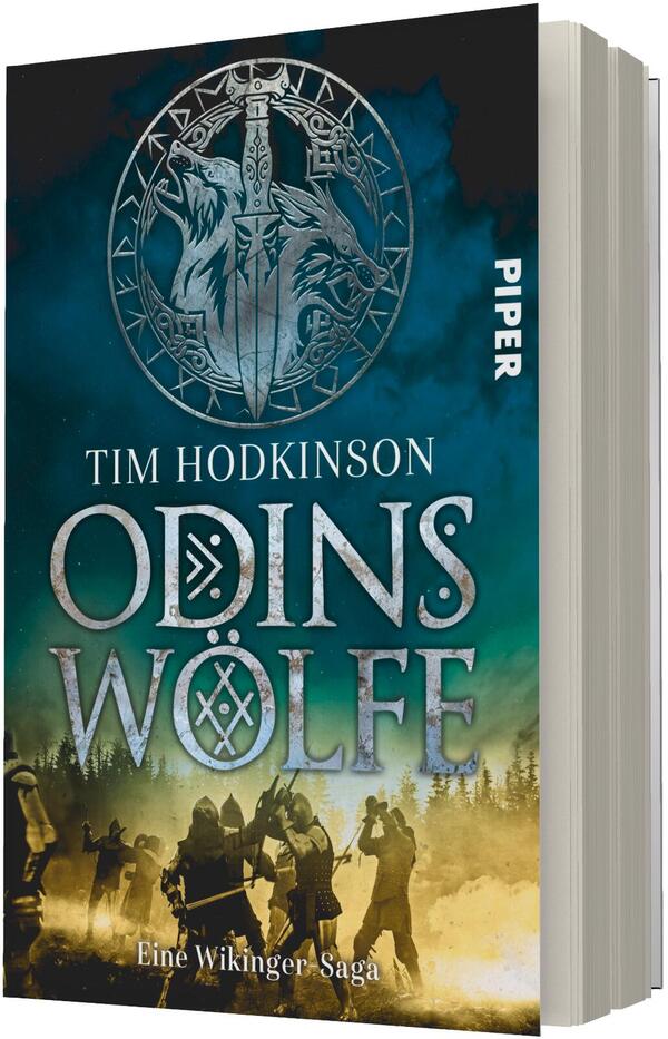 Das Buchcover zeigt vor einem dunkelgrün-blauen Himmel ein großes, silbernes Runenmedaillon mit zwei stilisierten Wolfsköpfen und einem vertikal angelegten Schwert. Darunter Name und Titel in großen, metallisch wirkenden Lettern: „Tim Hodkinson“ und „Odins Wolfe“, zusätzlich die Unterzeile „Eine Wikinger-Saga“. Im unteren Bereich silhouettenhafte Wikingerfiguren in gelblich beleuchteter Landschaft, stimmungsvolle, epische Atmosphäre. Verlagslogo nicht beschrieben.