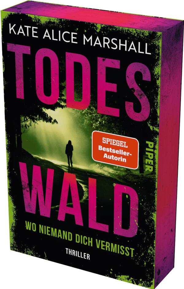 Das Buchcover zeigt eine düstere Waldszene mit nebligen Grüntönen. Im Vordergrund steht eine silhouettierte Figur, die in Richtung eines schmalen Weges blickt. Der Titel „TODESWALD“ ist in großen, auffälligen, pinken Buchstaben gestaltet, während der Untertitel „WO NIEMAND DICH VERMISST“ in einer schlichteren Schriftart darunter steht. Oben ist der Name der Autorin „KATE ALICE MARSHALL“ zu sehen, und ein orangefarbener Button mit dem Text „SPIEGEL Bestseller-Autorin“ hebt sich kontrastreich ab.