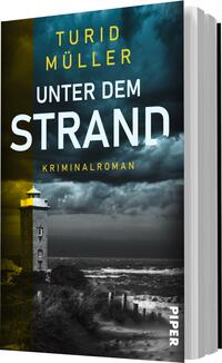 Das Buchcover zeigt einen dramatischen Küstenabschnitt mit einem Leuchtturm im Vordergrund. Die Farben sind in dunklen Blau- und Grautönen gehalten, während der Himmel mit drohenden Wolken gestaltet ist. Der Titel „UNTER DEM STRAND“ ist in großen weißen Buchstaben prominent platziert, während der Name der Autorin „TURID MÜLLER“ in leuchtendem Gelb darüber steht. Unter dem Titel ist der Zusatz „Kriminalroman“ zu finden. Die Gesamtatmosphäre vermittelt Spannung und Geheimnis.