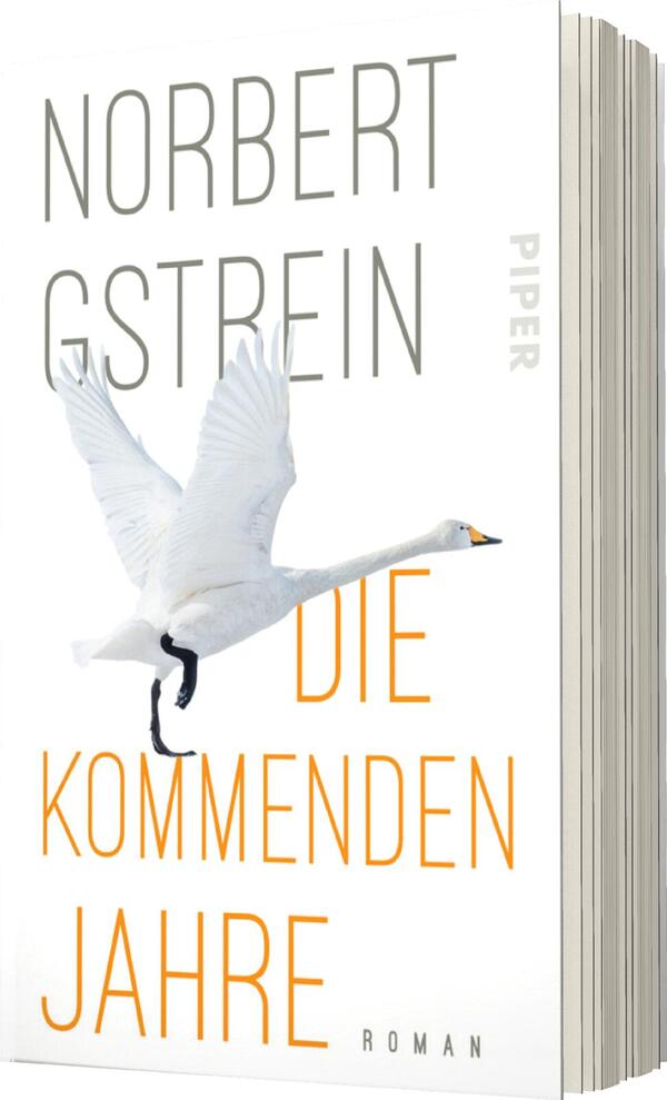 Das Buchcover zeigt einen weißen Schwan im Flug, der dynamisch von der unteren linken Ecke in die obere rechte Ecke des Covers kontrastiert. Der Hintergrund ist hell und schlicht, wodurch der Schwan stärker zur Geltung kommt. Der Titel „DIE KOMMENDEN JAHRE“ ist in kräftigem Orange in der Mitte platziert, während der Autorennamen „NORBERT GSTREIN“ in grauer, minimalistischer Schrift oberhalb steht. Die Atmosphäre des Covers wirkt zeitgenössisch und stilvoll.