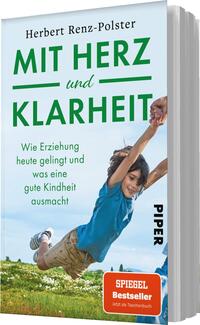 Das Buchcover zeigt den Titel „MIT HERZ und KLARHEIT“ in großen, grünen Buchstaben, während der Untertitel in schlichter Schrift „Wie Erziehung heute gelingt und was eine gute Kindheit ausmacht“ erscheint. Im Vordergrund sind ein Junge und ein Erwachsener zu sehen, die gemeinsam spielen und lachen, was eine fröhliche, positive Atmosphäre vermittelt. Der Hintergrund ist hell und vermittelt Weite, während unten links ein rotes Kästchen mit dem Text „SPIEGEL Bestseller – Jetzt als Taschenbuch“ zu finden ist.