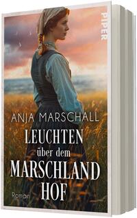 Das Buchcover zeigt eine junge Frau in historischer ländlicher Kleidung mit geflochtenem Haar und Kopftuch, die im Profil in ein gold-oranges Abendlicht über einem Schilf- bzw. Marschland blickt. Dominierende Farben sind warme Orange-, Rosa- und Grün-Töne. Die Titelschrift ist in großen weißen Serifbuchstaben gesetzt („LEUCHTEN über dem MARSCHLAND HOF“), darunter die Autorin Anja Marschall in kleinerer weißer Schrift.