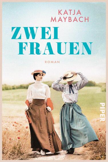 Das Buchcover zeigt zwei Frauen in historischer Kleidung, die auf einem Feld stehen. Die linke Frau trägt ein weißes Oberteil mit langen Ärmeln und einen braunen Rock, während die rechte Frau ein bläuliches Unterteil und einen weißen Oberteil mit einem großen Hut trägt. Der Hintergrund besteht aus grünem Gras und einem klaren Himmel. Der Titel „ZWEI FRAUEN“ ist in großen, aqua-blauen Buchstaben prominent platziert, darunter steht „ROMAN“ in kleinerer Schrift. Der Name der Autorin, Katja Maybach, steht oberhalb des Titels.