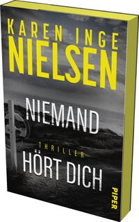Das Buchcover zeigt eine düstere Küstenlandschaft mit grauen und schwarzen Farbtönen, die eine spannungsgeladene Atmosphäre erzeugen. Im Vordergrund steht der Titel „NIEMAND HÖRT DICH“ in auffälliger weißer Schrift, während der Autorname „KAREN INGE NIELSEN“ in großen gelben Buchstaben oben platziert ist. Der Untertitel „Thriller“ ist in einer schmalen Schriftart in der Mitte des Covers abgebildet. Der Verlag „PIPER“ ist am unteren Rand angegeben.