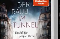 Das Buchcover zeigt eine düstere Stadtansicht mit leeren Straßen und grauen, historischen Gebäuden im Hintergrund. Über dem Titel „DER RAUB IM TUNNEL“ in auffälliger weißer Typografie prangt der Name des Autors „ULRICH WICKERT“ in großen Buchstaben. Die Farben sind hauptsächlich in Schwarz- und Grautönen gehalten, unterstrichen von einem roten Aufkleber mit dem Text „SPIEGEL-Bestseller-Autor“. Unten steht der Zusatz „Ein Fall für Jacques Ricou“.