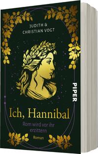 Das Buchcover zeigt eine goldene Illustration eines weiblichen Gesichts mit einem Lorbeerkranz, umgeben von stilisierten Pflanzenmotiven in gold auf einem dunklen, nahezu schwarzen Hintergrund. Der Titel „Ich, Hannibal“ ist in eleganter, geschwungener Schrift in goldenen Buchstaben platziert, während die Autorennamen „Judith & Christian Vogt“ in weißer Schrift am oberen Rand stehen. Im unteren Bereich des Covers ist der Hinweis „Roman“ in schlichter Schrift zu sehen. Die Gesamtatmosphäre vermittelt eine geheimnisvolle und historische Stimmung.