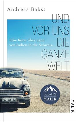 Das Buchcover zeigt ein nostalgisches Bild eines alten Autos, das auf einer weitläufigen, staubigen Straße steht. Der Himmel ist klar und blau, was eine weite Perspektive vermittelt. Der Titel „Und vor uns die ganze Welt“ ist in Großbuchstaben rechts auf dem Cover platziert, während der Untertitel „Eine Reise über Land von Indien in die Schweiz“ in kleinerer Schrift darunter steht. Unten rechts befindet sich ein rundes Logo mit dem Text „30 Jahre MALIK“.