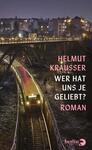 Das Buchcover zeigt eine nächtliche Szene mit einem beleuchteten Zug, der auf einer erhöhten Gleisführung fährt. Im Hintergrund sind unscharfe Wohngebäude zu erkennen, und die Atmosphäre wirkt melancholisch. Der Titel „WER HAT UNS JE GELIEBT?“ ist in prominentem, pinkfarbenem Schriftzug platziert, während der Urheber Helmut Krausser ebenfalls in pink, jedoch kleiner, darüber steht. Der Verlagsname „berlin verlag“ ist dezent am unteren Rand sichtbar.