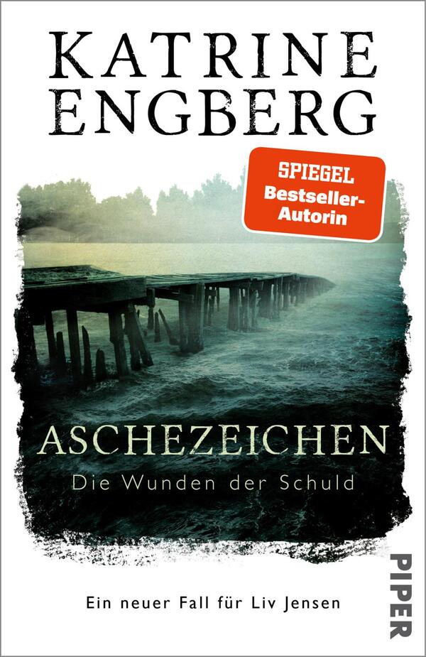 Das Buchcover zeigt eine düstere, neblige Szenerie mit einem Holzsteg, der ins Wasser führt. Die Farben sind in kühlen Blau- und Grautönen gehalten, was eine geheimnisvolle Atmosphäre erzeugt. Der Titel „ASCHEZEICHEN“ steht in großen, schwarzen Buchstaben, während der Untertitel „Die Wunden der Schuld“ in einer kleineren, helleren Schrift darunter platziert ist. Der Autorennamen „Katrine Engberg“ ist prominent oben in weißer Schrift zu sehen. Ein rotes Feld hebt den Text „SPIEGEL Bestseller-Autorin“ hervor.