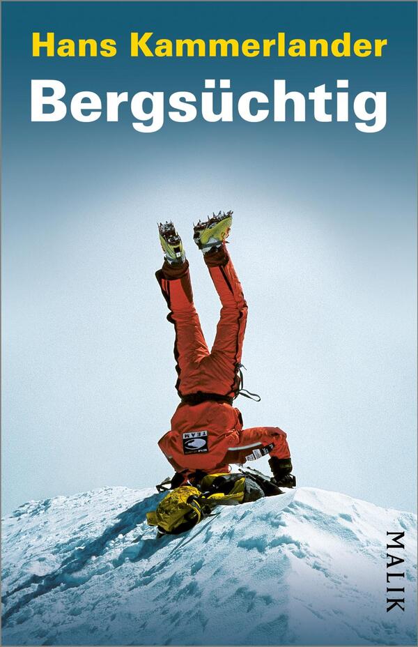 Das Buchcover zeigt einen am Gipfel auf dem Kopf stehenden Bergsteiger in rotem Anzug mit Steigeisen und gelbem Rucksack auf einer schneebedeckten Kuppe vor hellblauem, nach oben dunkler werdendem Himmel. Oben steht in gelber Schrift der Name Hans Kammerlander, darunter groß und weiß der Titel „Bergsüchtig“. Die Bildkomposition wirkt überraschend und surreal, kontrastreich in Farbe und Typografie.