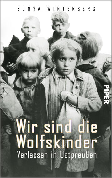 Das Buchcover zeigt eine schwarz-weiße Fotografie von Kindern in einer emotionalen, bedrückenden Stimmung. In der Mitte steht ein Mädchen mit blonden Haaren und traurigem Blick, umgeben von anderen Kindern, die ebenfalls ernst blicken. Der Titel „Wir sind die Wolfskinder“ ist in großer, weißer Schrift am unteren Rand platziert, darunter steht der Untertitel „Verlassen in Ostpreußen“ in kleinerer, grauer Schrift. Der Autorinnennamen „Sonya Winterberg“ befindet sich oben links in kleinerer Schriftgröße.