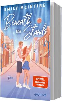 Das Buchcover zeigt ein junges Paar in der Bildmitte: ein Mann in weißem Tanktop und Shorts und eine rothaarige Frau in gelbem Top und blauem Rock, die einen Basketball hochwirft. Im Hintergrund eine perspektivisch dargestellte Kleinstadtstraße mit pastell-orangenen Häusern und weichem, himmelblauem Licht, die eine romantische, verträumte Stimmung erzeugt. Titel in großer, weißer Handschrift, Autorname „Emily McIntire“ oben in Großbuchstaben. Ein orangefarbener Button trägt den Text „SPIEGEL Bestseller-Autorin“.