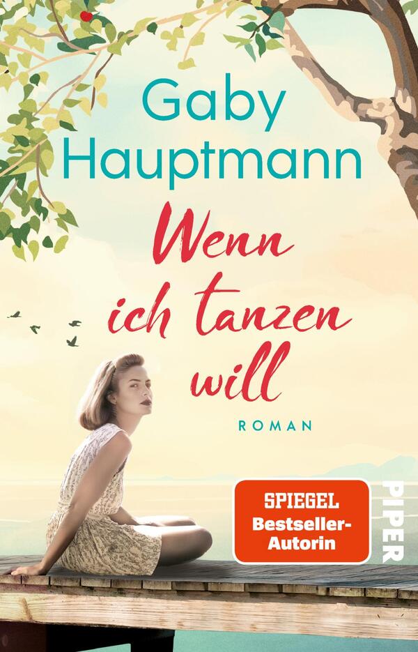 Das Buchcover zeigt eine junge Frau in hellgemustertem Kleid, die auf einem Holzsteg am Wasser sitzt, links oben ein blätterreicher Baum, einige kleine Vögel am Himmel; die Szene strahlt eine ruhige, sommerliche Stimmung aus. Auf pastellfarbenem Hintergrund steht oben in türkis die Autorin „Gaby Hauptmann“, mittig der Titel in roten, handschriftlichen Lettern „Wenn ich tanzen will“, unten klein „ROMAN“ in türkis. Oranger Button mit dem Text „SPIEGEL Bestseller-Autorin“.
