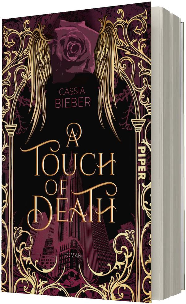 Das Buchcover zeigt ein dunkles, barock verziertes Design in Schwarz, Dunkelrot und Gold mit floralen Ornamenten und goldenen Engelsflügeln oben. Zentraler Titel in geschwungener goldener Typografie: „A Touch of Death“. Autorname „Cassia Bieber“ steht in kleiner roter Schrift oberhalb, darunter in dunklem Rot angedeutete Wolkenkratzer und die Wortmarke „Roman“. Auf dem Buchrücken vertikal „PIPER“.