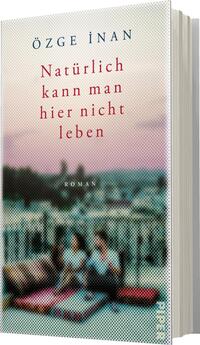 Das Buchcover zeigt eine unscharfe Darstellung von zwei sitzenden Frauen auf einem Balkon, umgeben von urbaner Szenerie. Der Hintergrund ist in sanften Pastellfarben gehalten, die an einen Sonnenuntergang erinnern, mit einer leicht verschwommenen Ansicht von Gebäuden. Der Titel „Natürlich kann man hier nicht leben“ ist in kräftigem Rot gesetzt, während der Autorenname „Özge İnan“ in einem dezenten Blau oben auf dem Cover steht. Der Untertitel „Roman“ ist in kleinerer Schriftgröße unter dem Titel platziert.