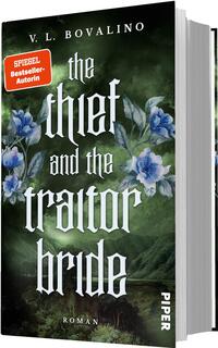 Das Buchcover zeigt einen dunkelgrünen, nebligen Landschaftshintergrund mit blau-violetten Blumen im Vordergrund. Oben steht der Autorenname „V. L. Bovalino“. Der Titel „the thief and the traitor bride“ ist mittig in großer weißer, gotischer, ornamentaler Schrift gesetzt. Ein orangefarbener Aufkleber-Button links oben trägt die Aufschrift „SPIEGEL Bestseller-Autorin“. Unten steht klein „ROMAN“. Gesamtwirkung: geheimnisvoll, düster-romantisch.