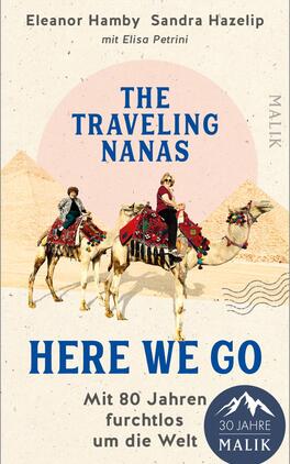 Das Buchcover zeigt zwei ältere Frauen, die auf Kamelen sitzen und mit bunten Tüchern und dekorativen Sätteln geschmückt sind. Im Hintergrund sind Pyramiden vor einem hellen, runden Himmel erkennbar. Der Titel „THE TRAVELING NANAS“ ist in großen, blauen Buchstaben oben platziert, während „HERE WE GO“ in einer etwas kleineren, rosanen Schrift darunter steht. Der Untertitel „Mit 80 Jahren furchtlos um die Welt“ ist in einer dezenten, grauen Schrift gehalten. Die Farbgebung vermittelt eine warme, abenteuerliche Atmosphäre.