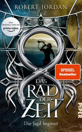 Das Rad der Zeit 2 Das Buchcover zeigt einen fantasievollen, düsteren Hintergrund in Blau- und Grautönen. Im Zentrum ist ein geschwungener, silberner Drache zu sehen, der sich um ein unendliches Symbol windet. Darüber erhebt sich eine stilisierte Figur mit einem Bogen, die in die Ferne blickt. Die Titelgestaltung in großen, kräftigen Buchstaben hebt sich deutlich ab, während die Unterzeile „Die Jagd beginnt“ kleiner und in einer anderen Schriftart platziert ist. Oben links prangt ein Hinweis auf die „prime video“-Serie, während ein rotes Kästchen mit „Spiegel Bestseller“ einen zusätzlichen Akzent setzt.